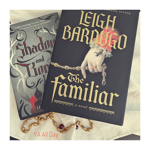Original photo of The Familiar by Leigh Bardugo and Shadow and Bone. They are on white linen with a gold chain and red crystals.